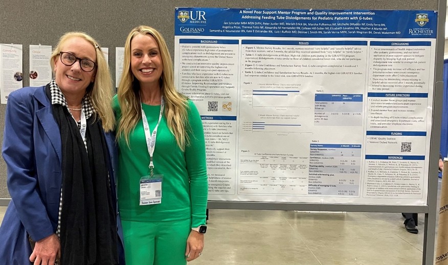 two women standing in front of GCH poster